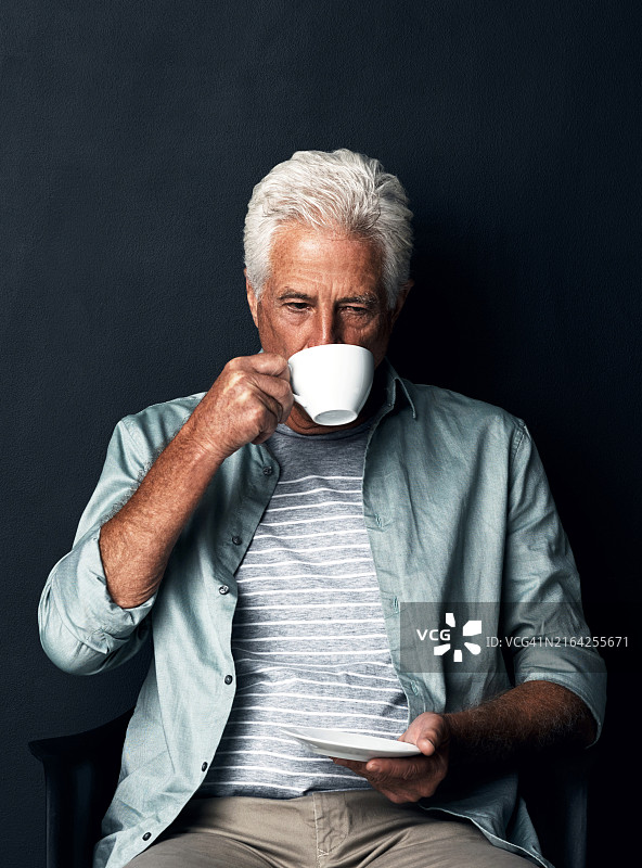 在黑色背景下喝茶的年长男人图片素材