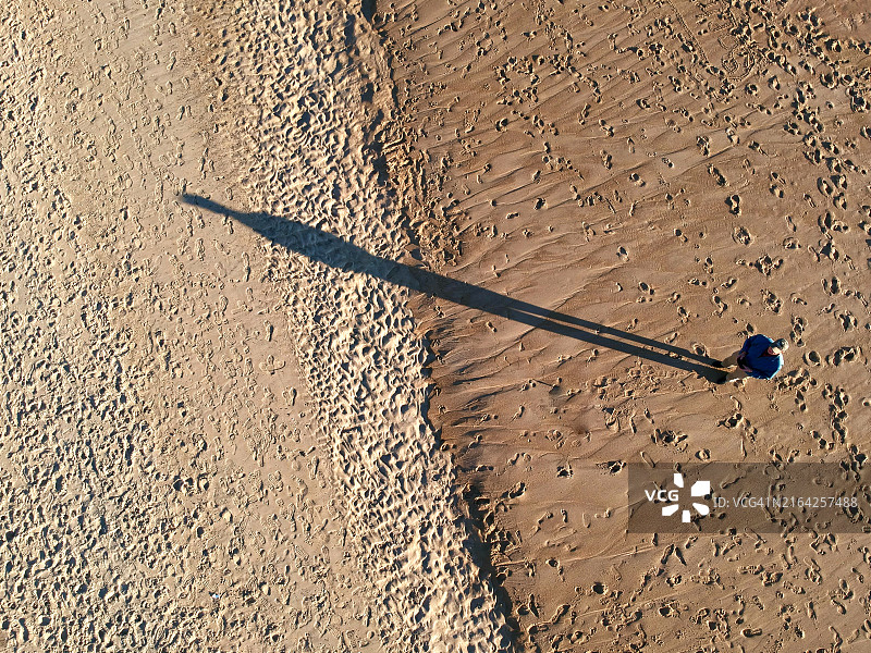 俯视角度拍摄的男子及其在特拉华州芬威克岛和伯大尼海滩之间海滩上的影子图片素材