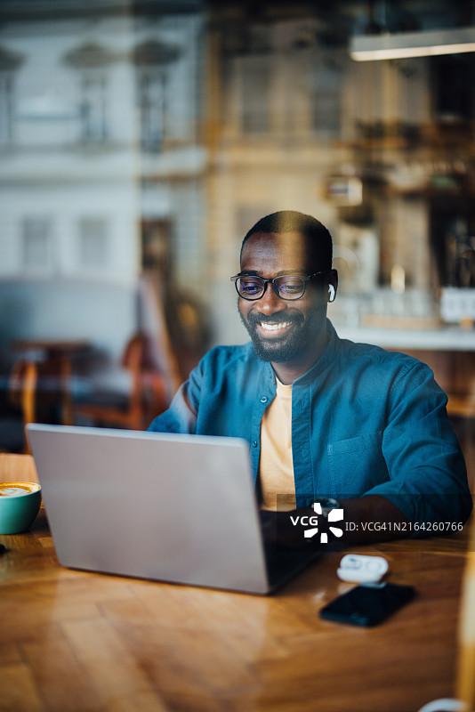 在舒适咖啡馆里用笔记本电脑工作的男人图片素材