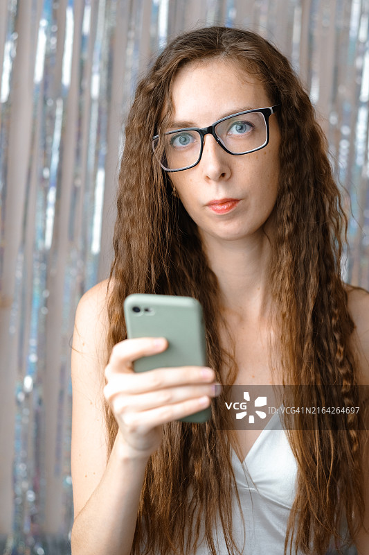 长发蓝眼美女戴着眼镜在闪光背景下发短信图片素材