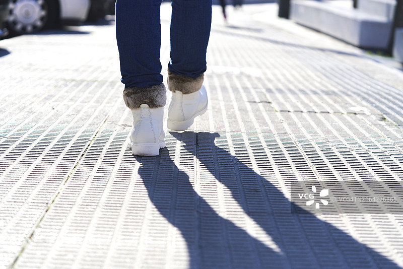 雪地靴在公园沥青路面上行走的人的特写，鞋底较脏，后视图图片素材