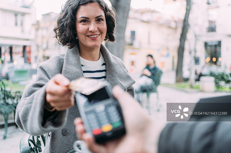 在咖啡馆用信用卡非接触式支付的年轻女子图片素材