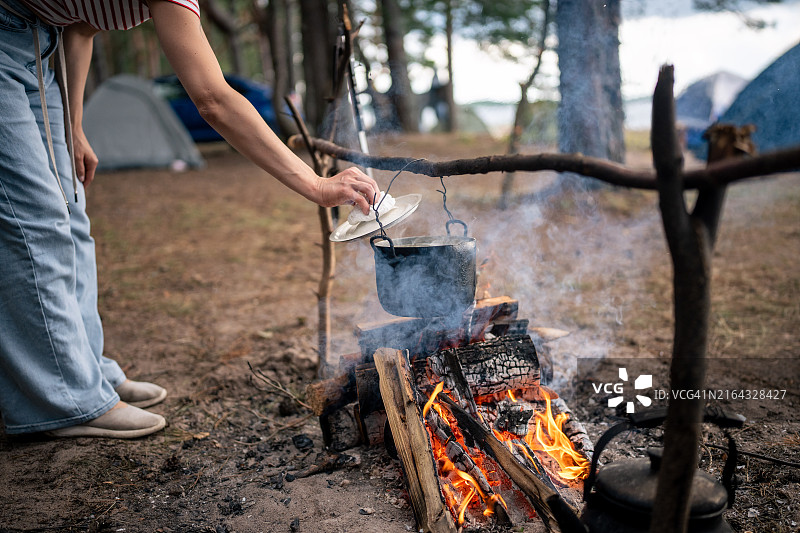 女游客在野外营地用篝火煮午餐和晚餐图片素材