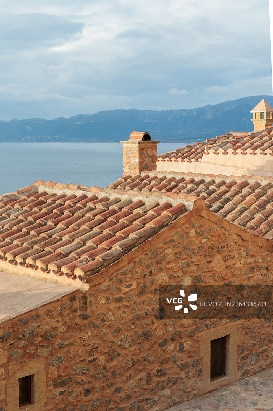 蓝色大海背景下的瓦屋顶石头房子，希腊莫奈姆瓦夏中世纪村庄的景色图片素材