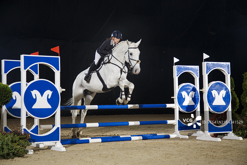 年轻女人和马一起跳过障碍图片素材