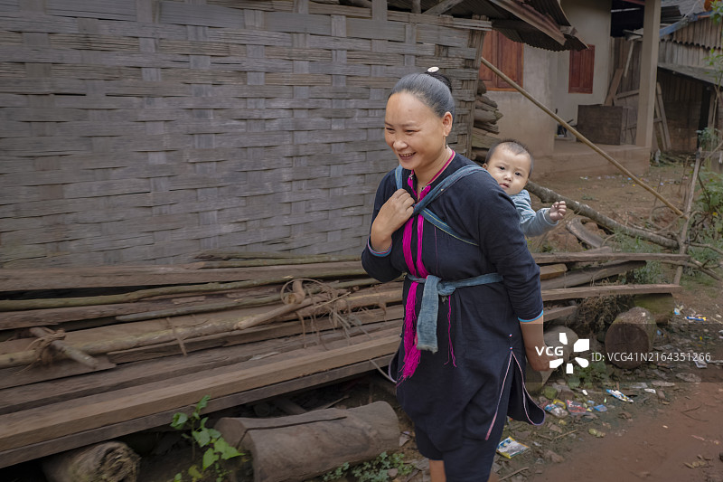 老挝北部村庄里背着婴儿的母亲图片素材