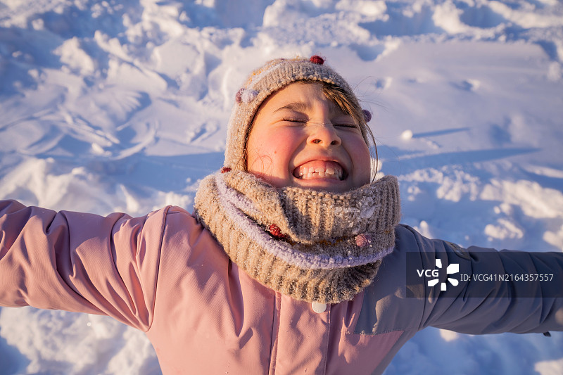 快乐的女孩在雪地里表达喜悦之情图片素材