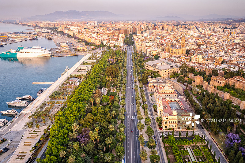 西班牙马拉加市中心鸟瞰，展示了城市、主要林荫大道和带船只的港口图片素材