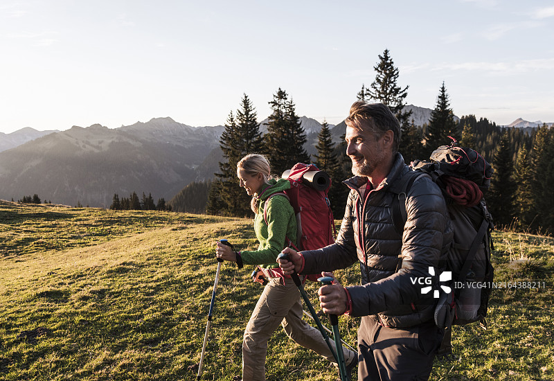 快乐情侣在蒂罗尔山上手持登山杖图片素材
