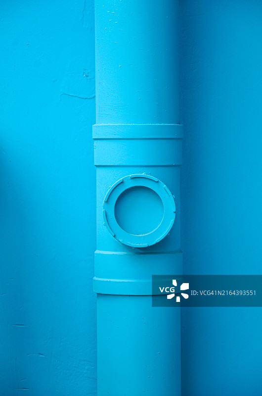连接在蓝色墙壁上的排水管道图片素材