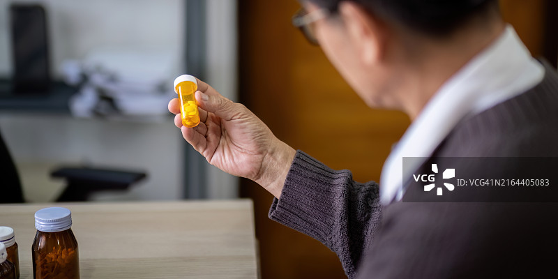 年长的亚洲男人在家检查处方药图片素材