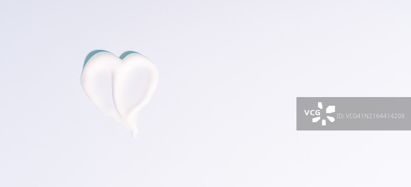 蓝色背景上心形的白色奶油涂抹图片素材