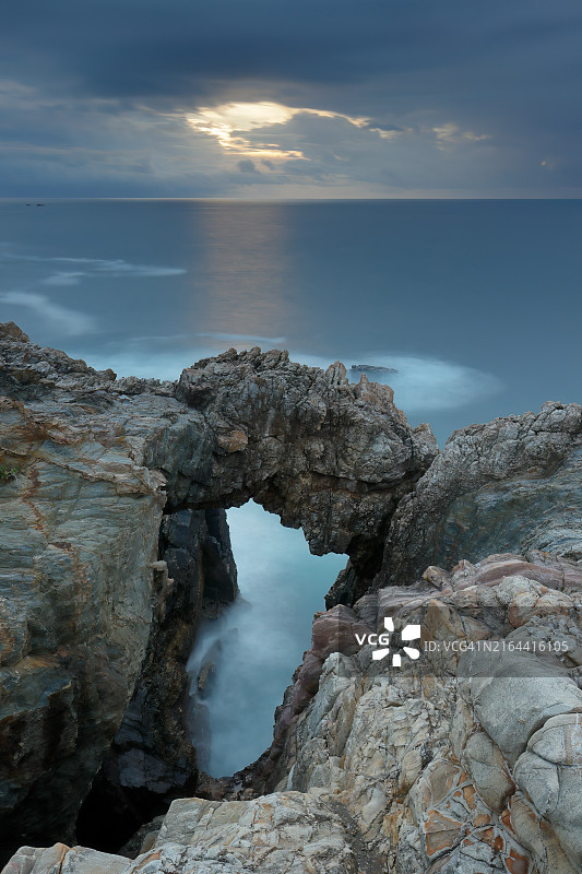 西班牙阿斯图里亚斯西部阿斯图里亚斯海岸暴风雨日落下的石拱门图片素材