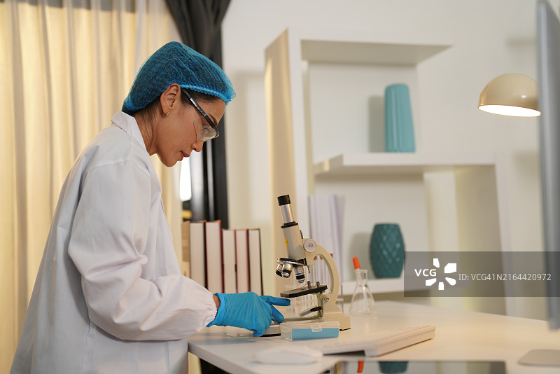 女医生在工作台上用显微镜观察图片素材