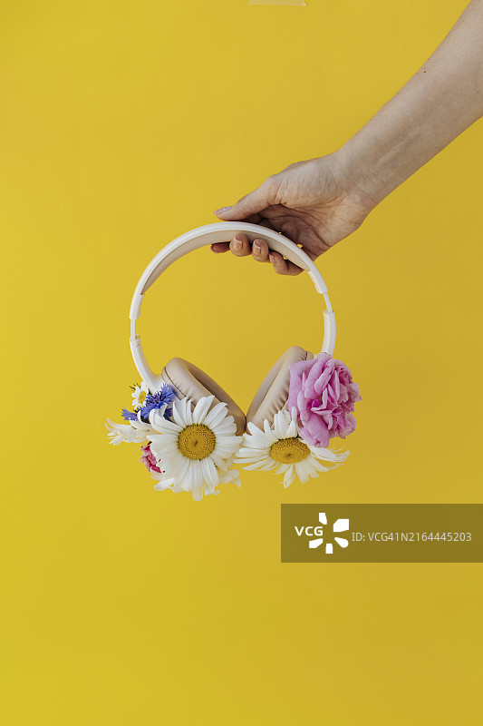 女人手持鲜花装饰的耳机图片素材