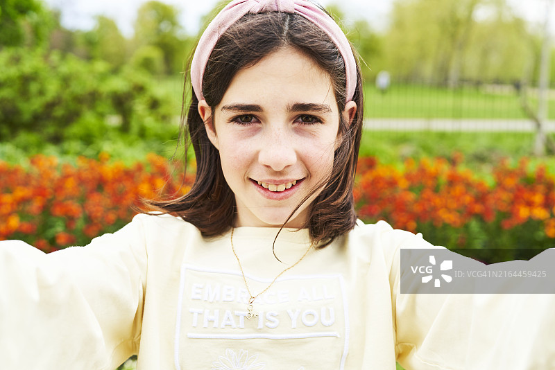 棕发少女在户外郁金香花丛中自拍图片素材