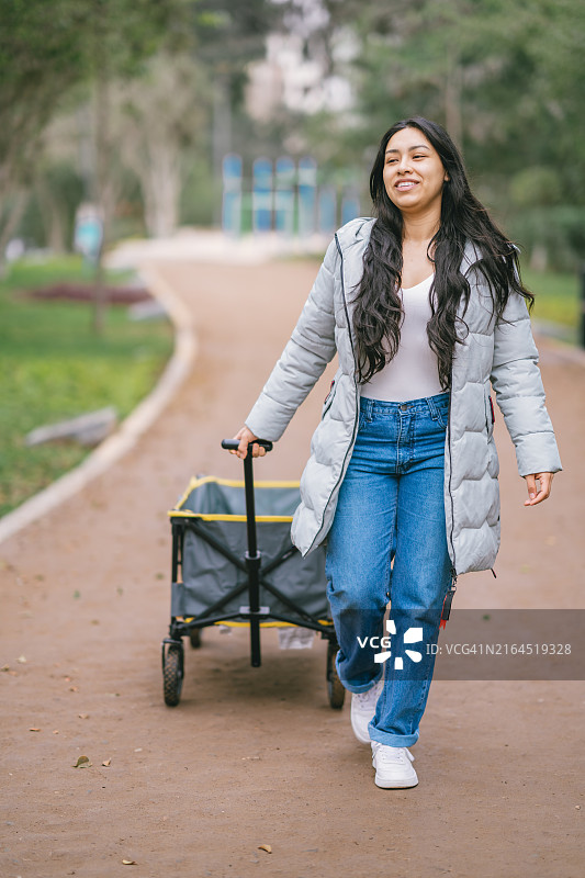 年轻女子在公园里拉着折叠手推车图片素材