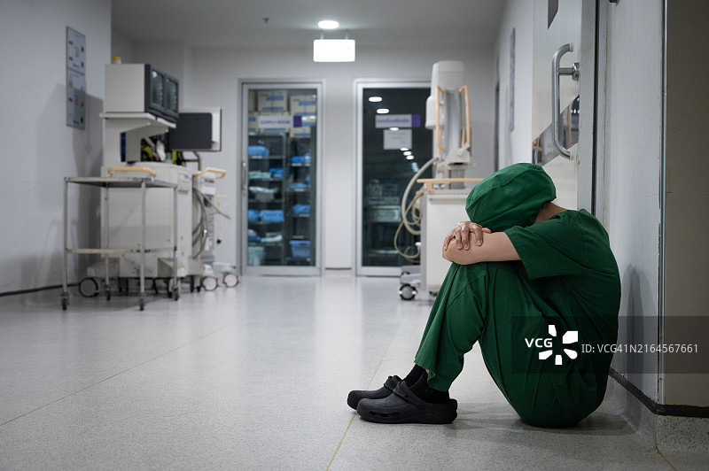 手术失败后，坐在医院地板上感到压力和悲伤的医护人员图片素材