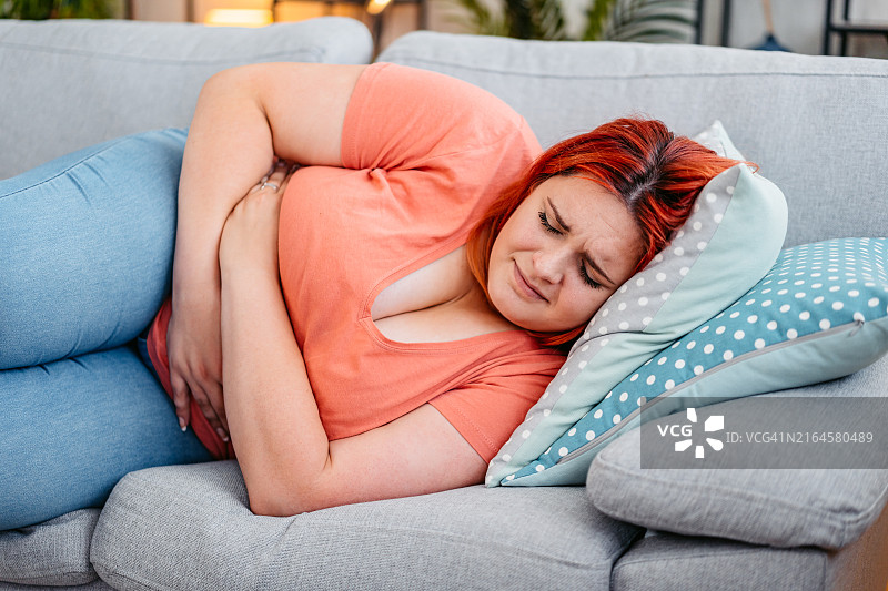 年轻女人在家中经期痉挛图片素材