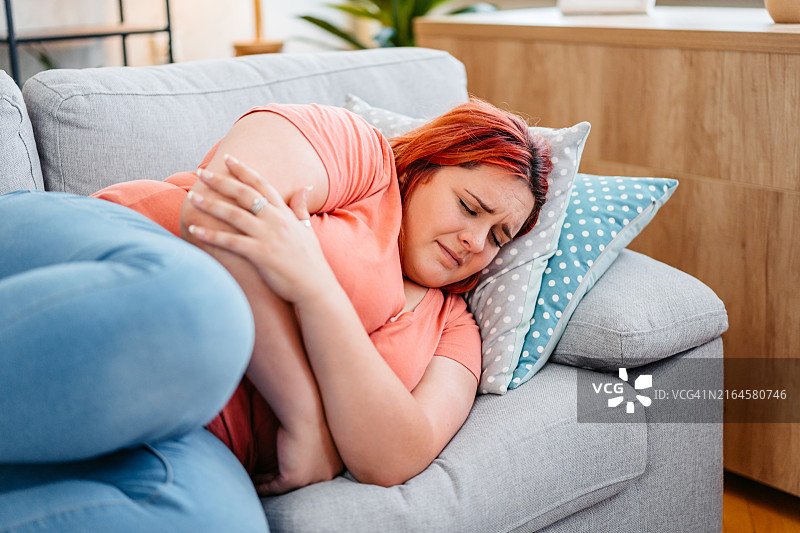 年轻女人在家中经期痉挛图片素材