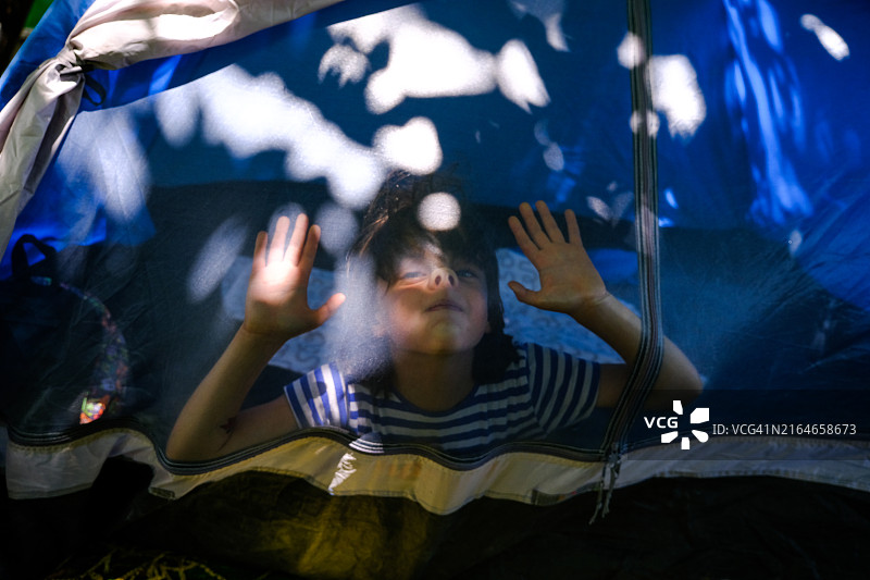 小男孩在帐篷里玩耍。家庭露营图片素材