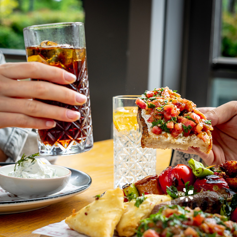 人们在桌子上端着饮料的局部照片图片素材