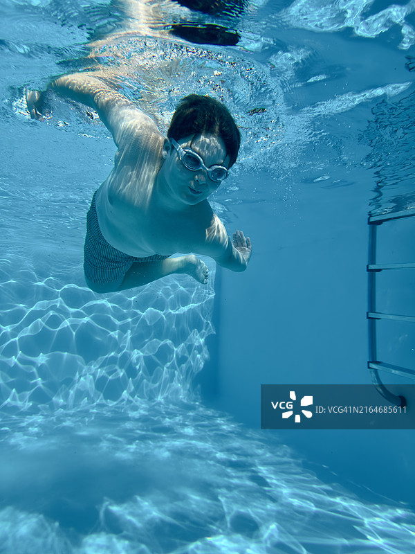 男孩和父亲、弟弟在泳池里游泳，水下人像，家庭乐趣图片素材