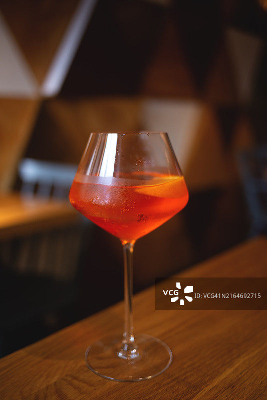 木桌上高脚杯中的清爽橙色鸡尾酒，适合放松的夜晚图片素材