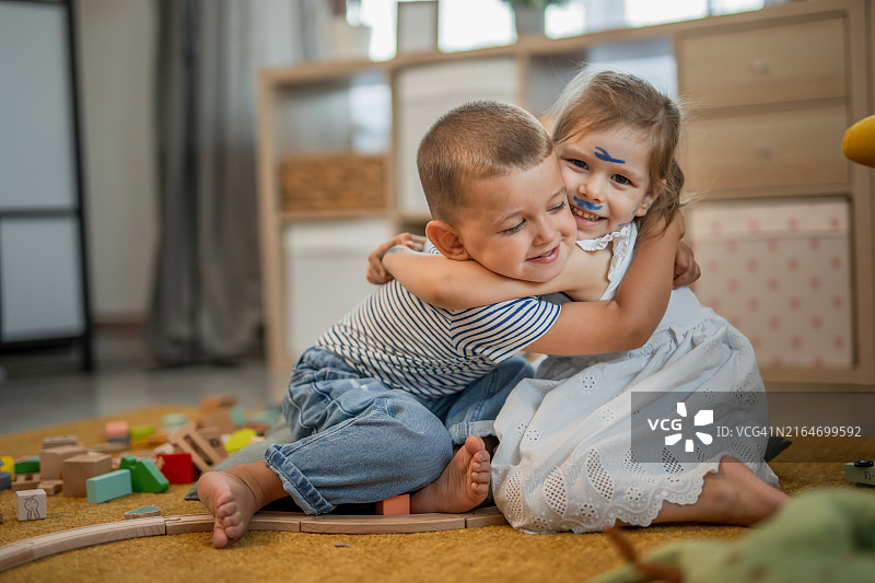 两个幼儿在地板上拥抱玩耍，促进儿童早期情感发展图片素材