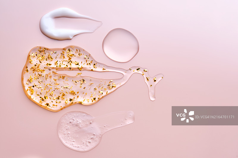 粉色背景上的面部精华、霜、油和含24K金精华液纹理图片素材