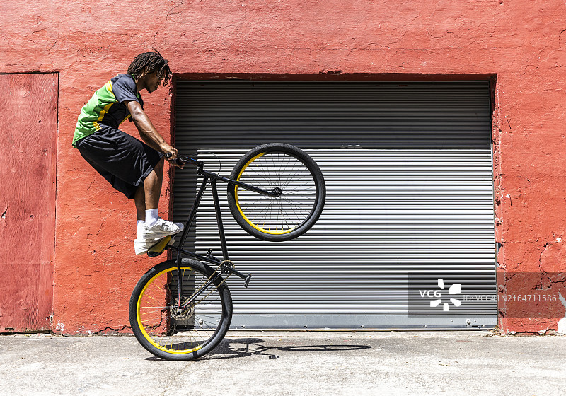 自行车手在红色工业建筑前表演特技图片素材
