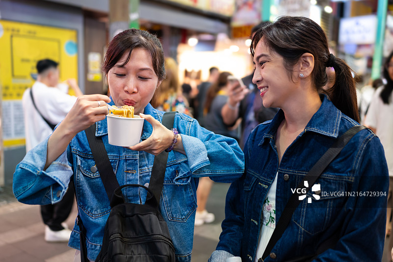 两位亚洲女性游客在中国台湾台北西门町夜市品尝美味米粉图片素材