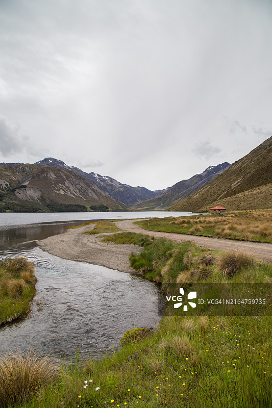阴天夏天特尼森湖克拉伦斯河上游的土路，远处有露营地，新西兰坎特伯雷图片素材