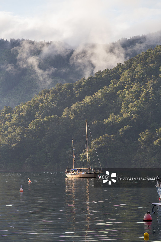 马尔堡莫莫朗吉湾平静水面上的系泊船和海雾山脉图片素材
