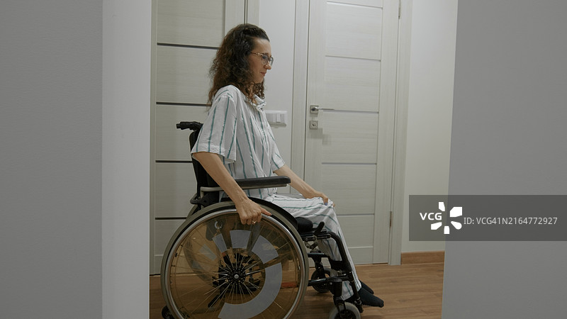 坐在轮椅上的女人在家中走廊移动图片素材