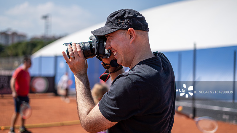 男子运动摄影师在红土球场网球锦标赛上拍摄照片图片素材