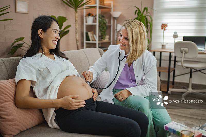 医护人员上门拜访孕妇，检查孕妇的腹部和胎儿的心跳图片素材