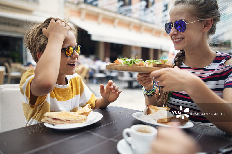 在户外餐厅享用热三明治的儿童肖像图片素材
