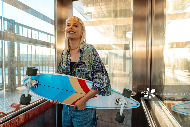 在电梯里拿着长板的美丽都市年轻女性图片素材