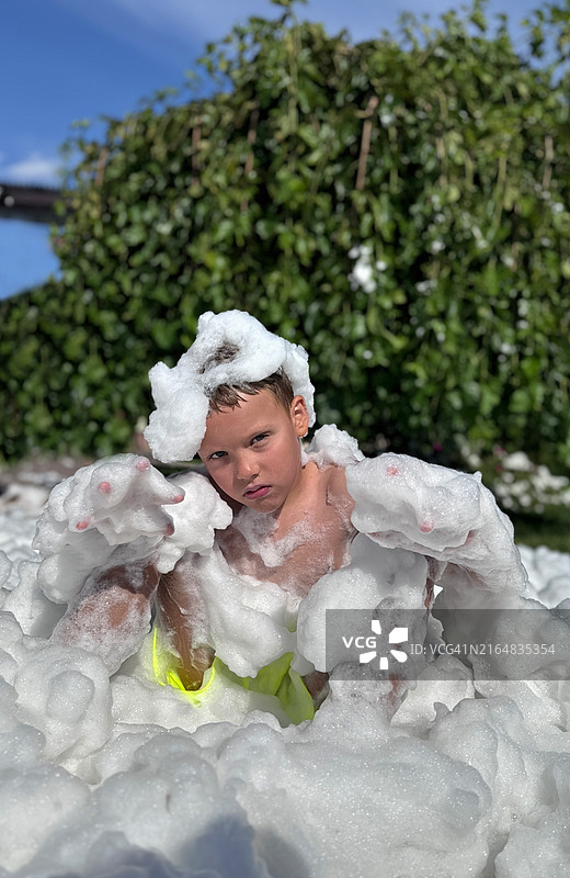 泡沫派对后，男孩坐在泡沫中图片素材