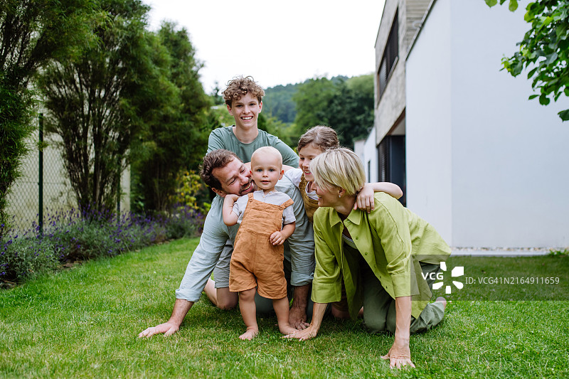 拥有三个孩子的年轻漂亮家庭的肖像。在房子前户外的核心家庭。图片素材