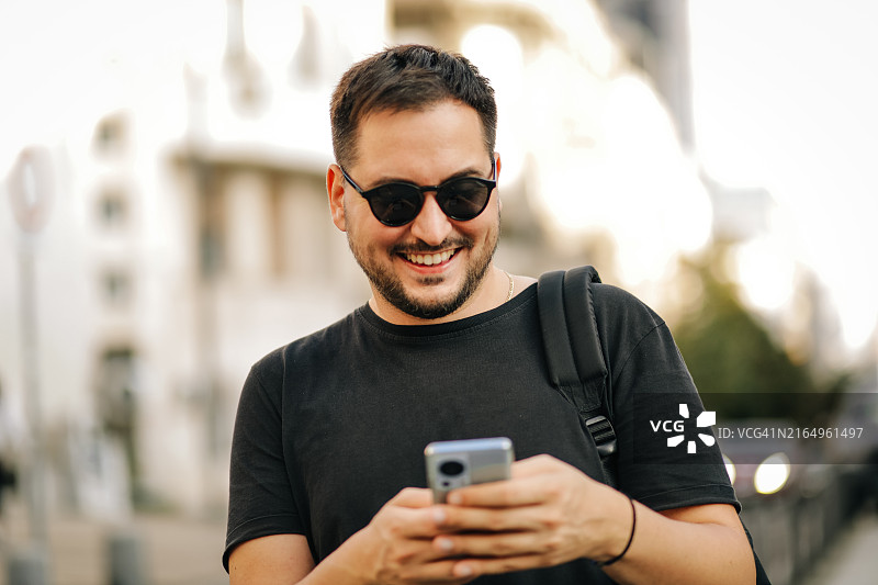 在城市街道上使用手机的年轻男人图片素材