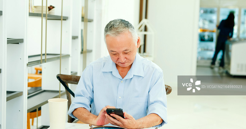 老年亚洲男顾客在咖啡馆手机支付图片素材