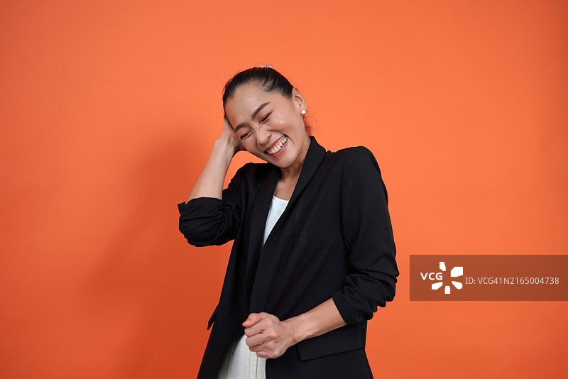 夏季人像：穿着黑色西装的女人站在橙色背景上图片素材
