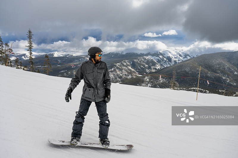 黑人男人在美丽的科罗拉多风景中单板滑雪图片素材