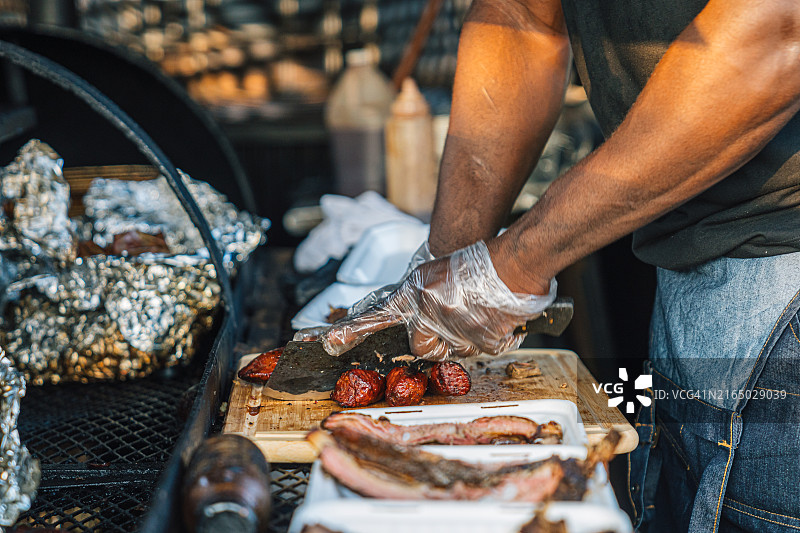 烧烤专家厨师为餐车或餐饮公司切熏猪肉香肠图片素材