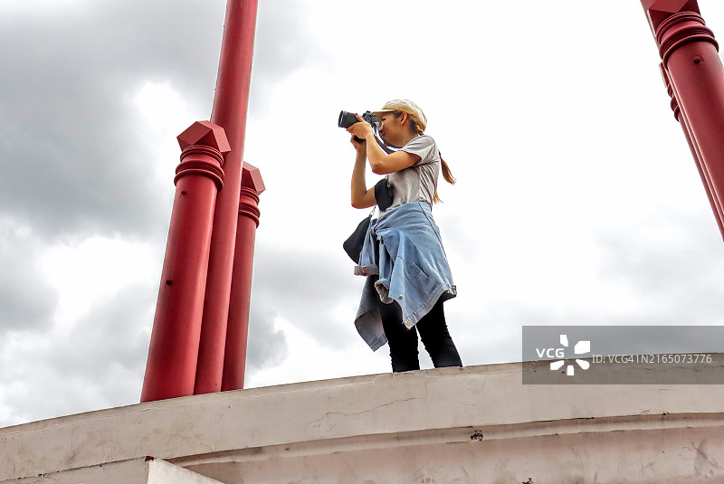 拿着相机看屏幕的年轻亚洲女游客图片素材