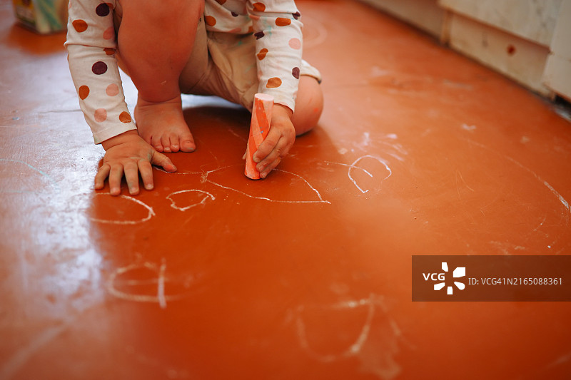 顽皮的创意：孩子用粉笔在地板上画画图片素材