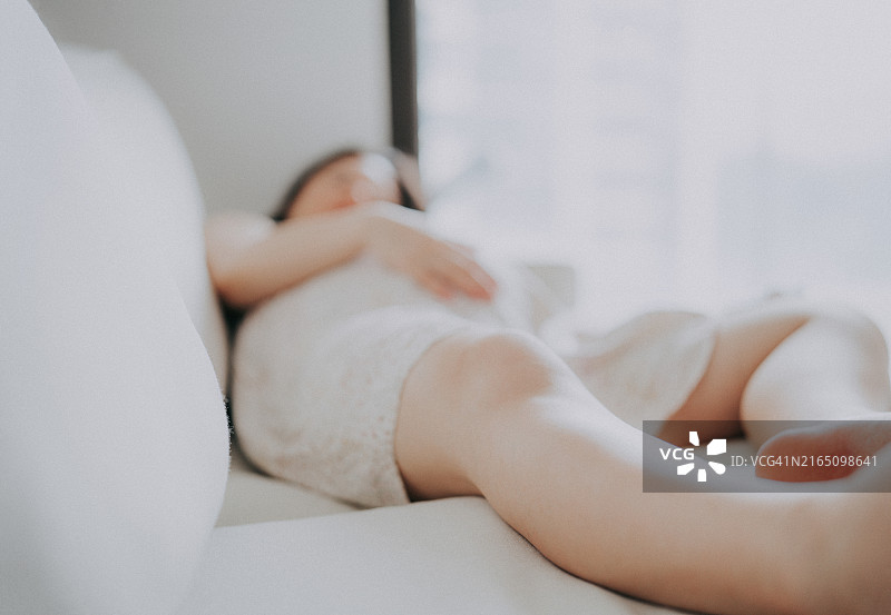 年轻的亚洲女性在沙发上睡觉图片素材