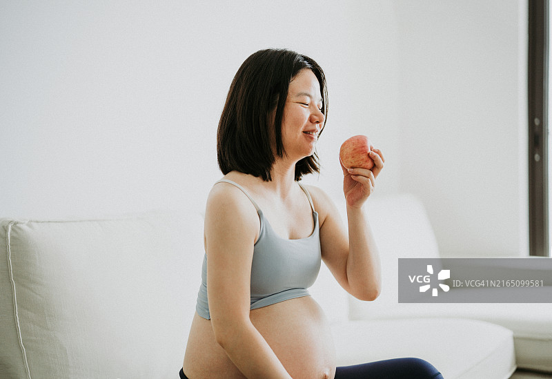 一位年轻的亚洲孕妇正在吃水果图片素材